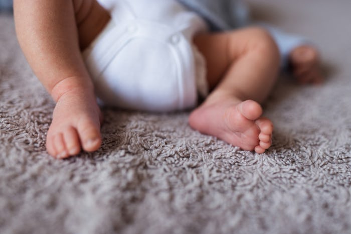 Baby legs and bottom in diaper on bed