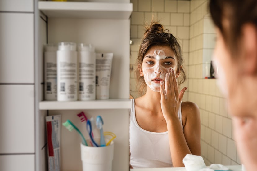 Teen girl washing her face in the bathroom, in a story about kid-safe skin care.