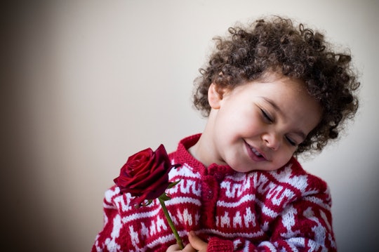 Two years old girl is holding a red rose