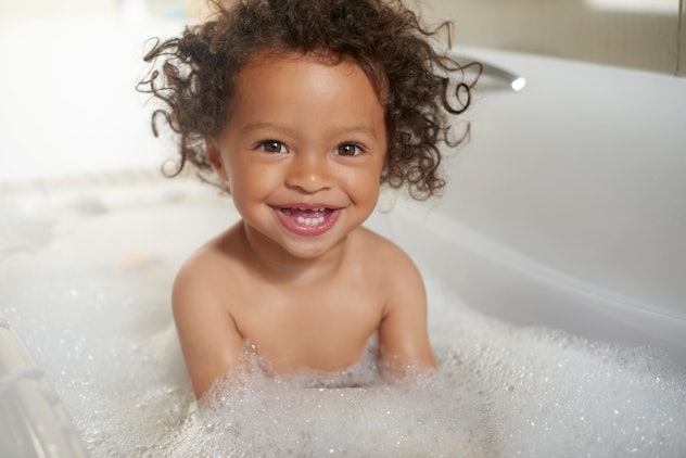 Bathtub, portrait and happy girl laughing in water, soap and foam for washing, hygiene and kids at h...