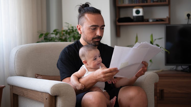 Young father working at home office with baby girl