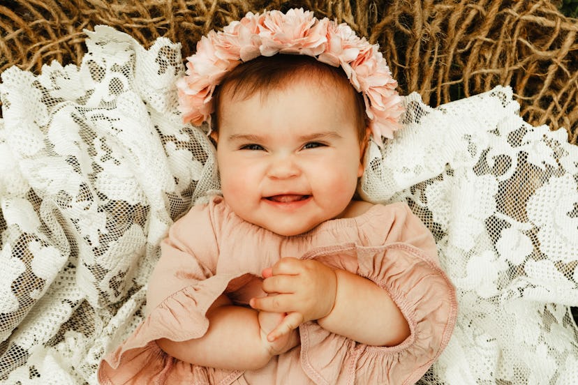 A beautiful baby girl, seven months old, smiling at the camera.