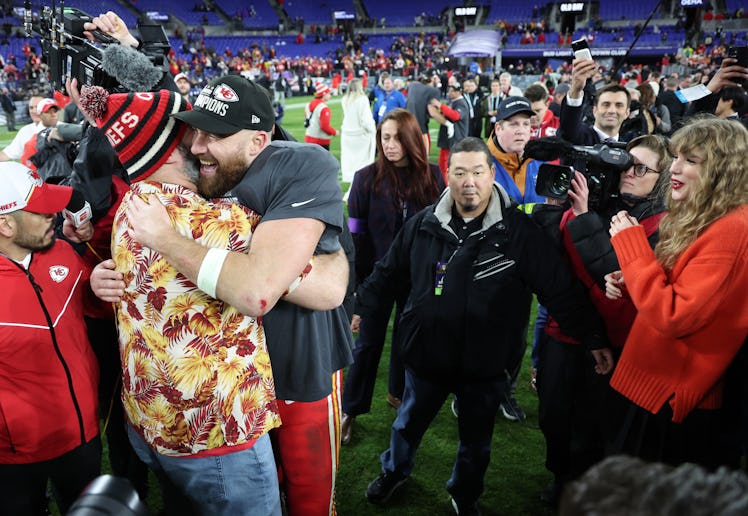 Travis Kelce and Jason Kelce hugging after the AFC Championship Game, with Taylor Swift looking on