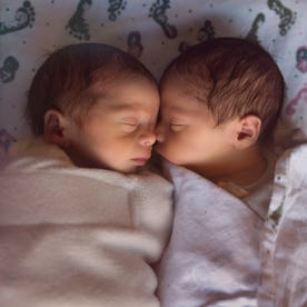 newborn male fraternal twins sleep peacefully after birth together swaddled and together in their cr...