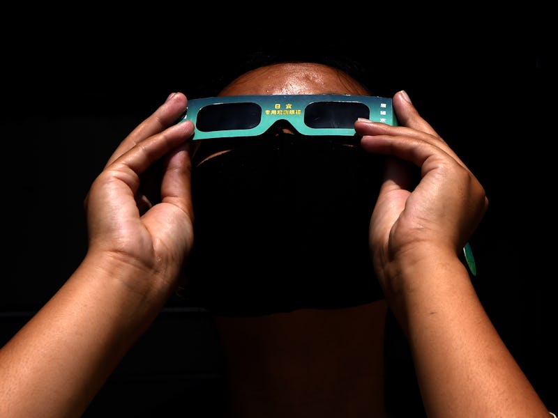 A bystander wears a pair of viewing goggles to watch an annular solar eclipse in Kathmandu on June 2...