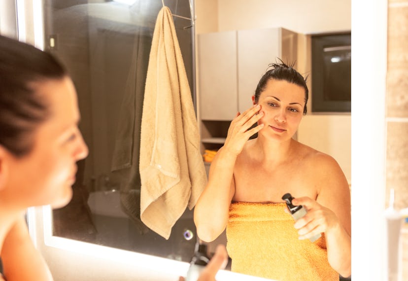Woman applying face moisturizer in the bathroom