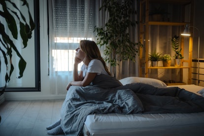 Depressed mid-adult woman sitting in bed, suffering from insomnia