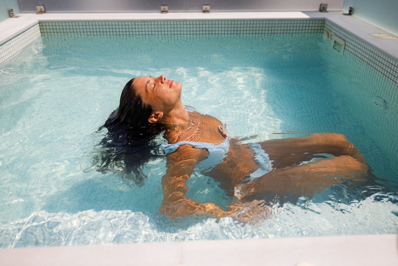 Young smiling woman relaxing in hot tub during her summer vacation. Copy space.