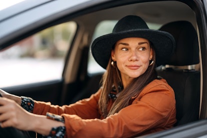 Beautiful woman with a hat is driving a car