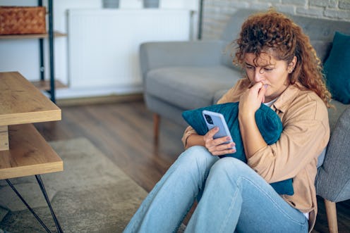 Depressed woman sitting on floor with mobile phone