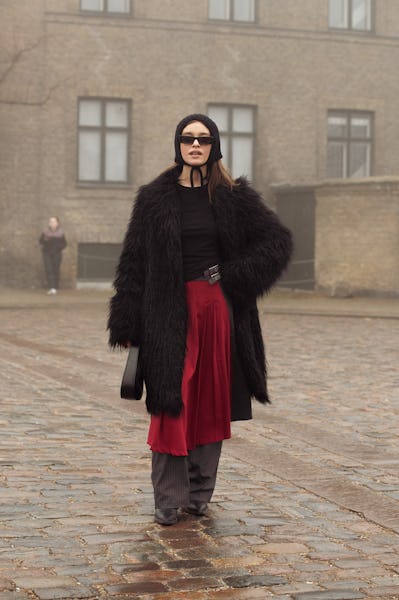 COPENHAGEN, DENMARK - JANUARY 30: A guest wears grey pants, red skirt, black top, black hat, and bla...