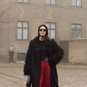 COPENHAGEN, DENMARK - JANUARY 30: A guest wears grey pants, red skirt, black top, black hat, and bla...