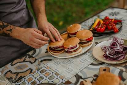 Man serves up a stack of burgers from his backyard grill