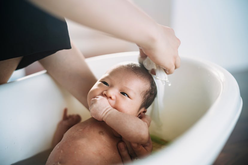 Cropped shot of mother bathing her newborn baby in bathtub, in a story answering the question when w...