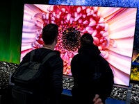 04 September 2022, Berlin: Visitors look at televisions at the stand of the LG brand at the electron...