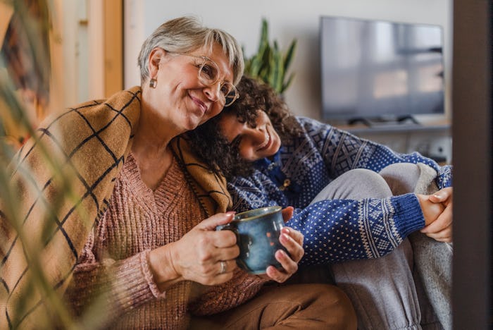 Grandma and granddaughter smiling and cuddling on a couch with a mug, in a story about a viral TikTo...