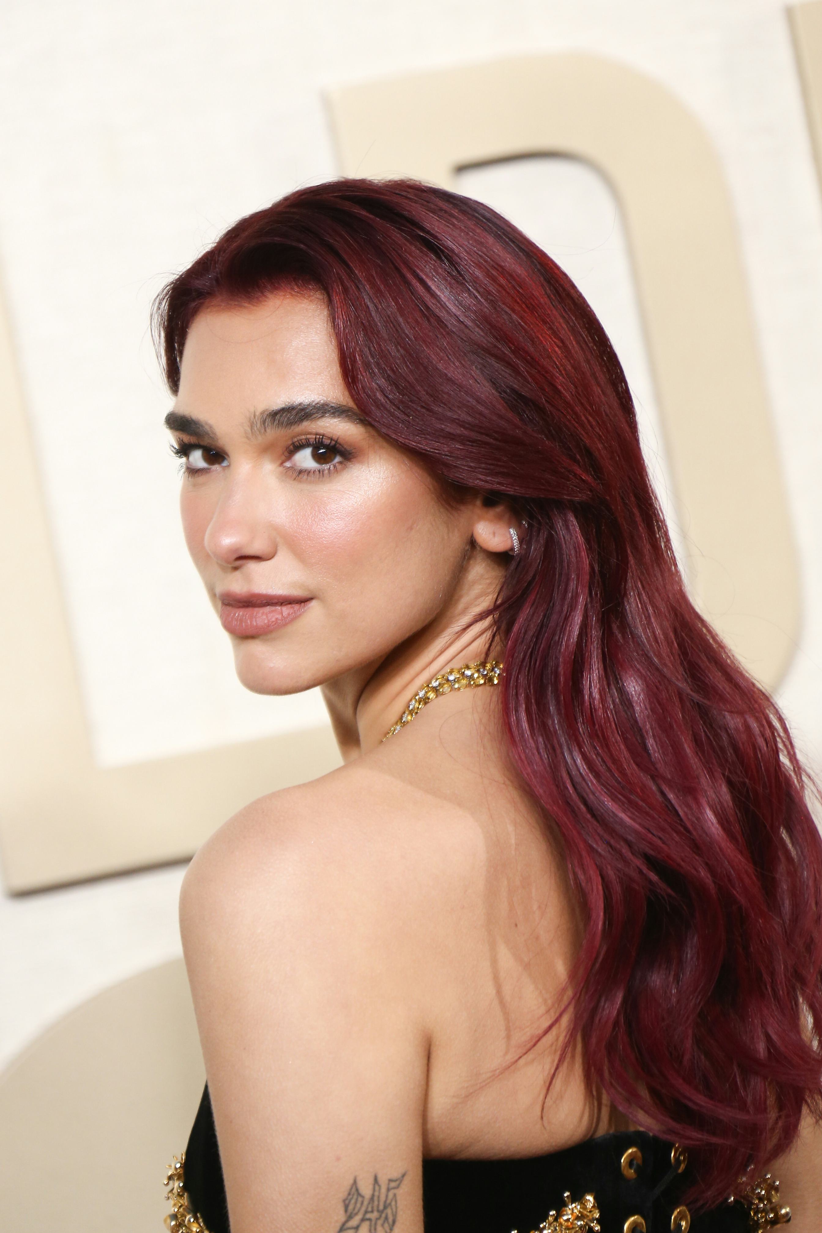 Dua Lipa&rsquo;s soft beat makeup and cherry coke hair at the 2024 Golden Globe Awards.