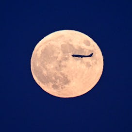 BEIJING, CHINA - SEPTEMBER 29: An airplane flies across the super moon on September 29, 2023 in Beij...