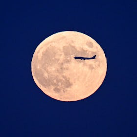 BEIJING, CHINA - SEPTEMBER 29: An airplane flies across the super moon on September 29, 2023 in Beij...