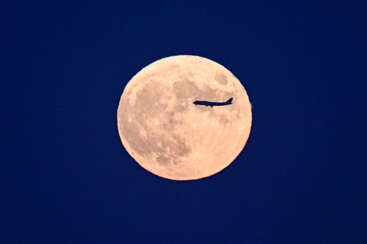 BEIJING, CHINA - SEPTEMBER 29: An airplane flies across the super moon on September 29, 2023 in Beij...