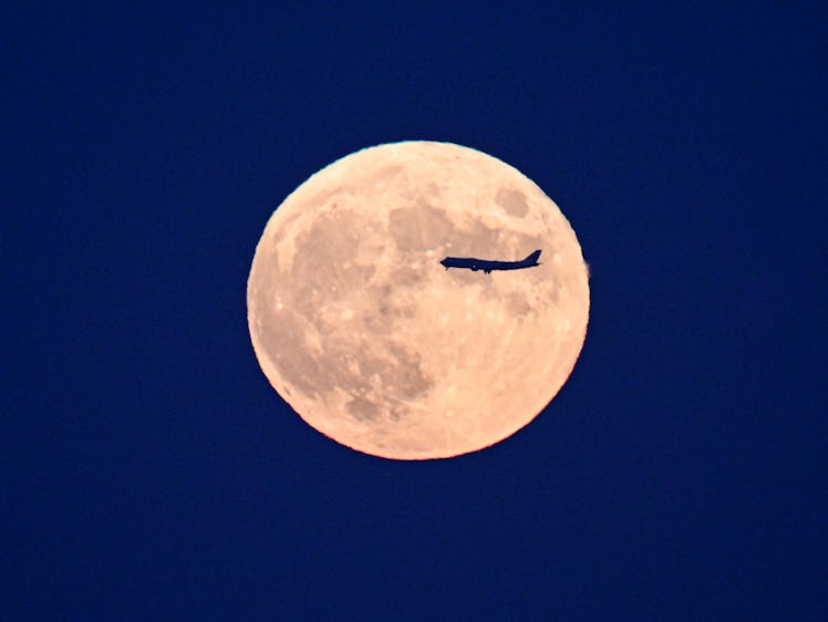 BEIJING, CHINA - SEPTEMBER 29: An airplane flies across the super moon on September 29, 2023 in Beij...