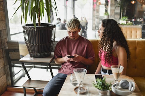 Female trying to get boyfriend's attention while drinking coffee in bar