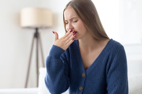 Ill woman covering her mouth with negative emotion