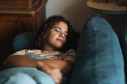 Young woman with curly hair relaxing on the couch at home