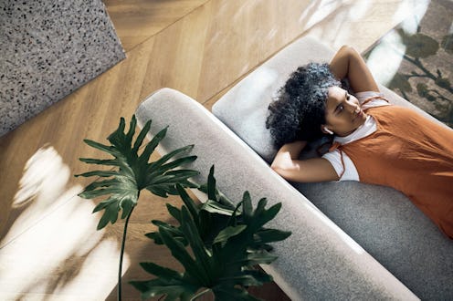 Woman zen, relax and sleeping on the couch or sofa while listening to music or a podcast in the livi...