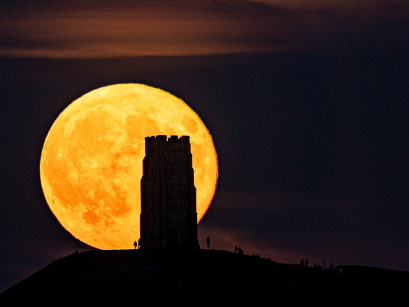 People gather as the supermoon rises over St Michael's Tower, atop Glastonbury Tor, which occurs whe...