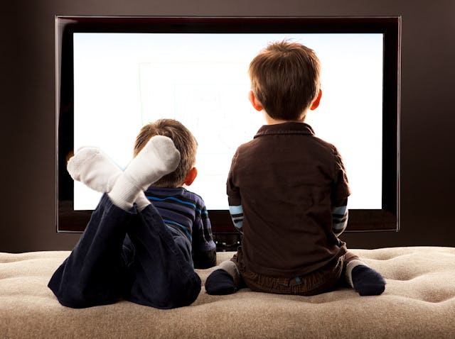 Two half Asian Brothers sitting and laying down on a day bed in front of a large flat screen TV on l...