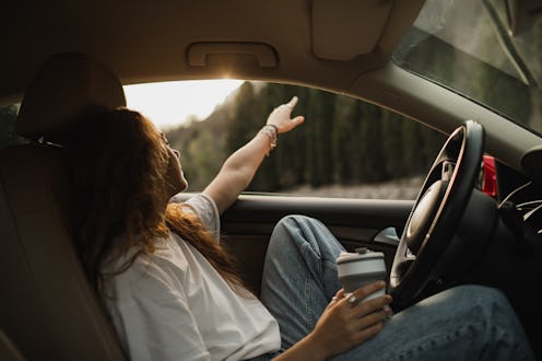 Woman relaxing alone in car, lonely mood. Beautiful sunset through window. Solitude and tranquility.