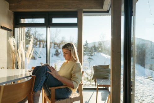 Photo of a young woman spending a sunny winter day in a cabin house