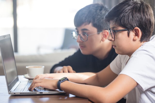 Two boys working together on a laptop computer