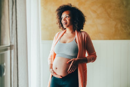 Pregnant woman at home looking through the window