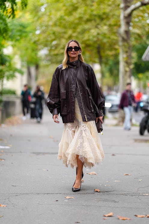 PARIS, FRANCE - SEPTEMBER 30: Candela Novembre wears black sunglasses, gold earrings, shiny dark bro...