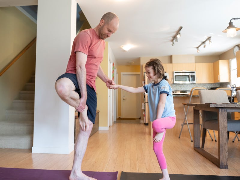 Father and daughter perform yoga in a brightly lit, modern home, Whistler, B.C.