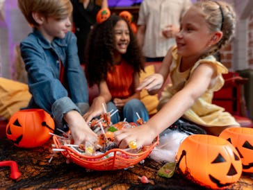 Multiracial children celebrating Halloween party together in house. Lovely family dressed in Hallowe...