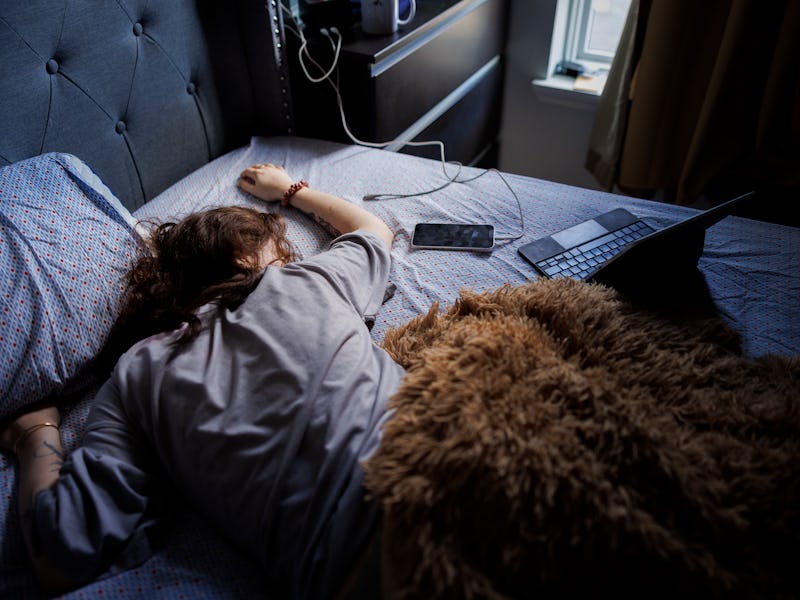 Bad sleeping habits of young woman in bed. Tired woman sleeping after restless night with gadgets