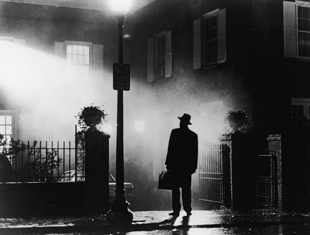 A silhouette of a man stands in front of a house at night in a still from the film,' The Exorcist', ...