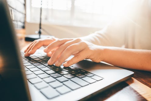 Woman working at home office. Close up hand on laptop keyboard.