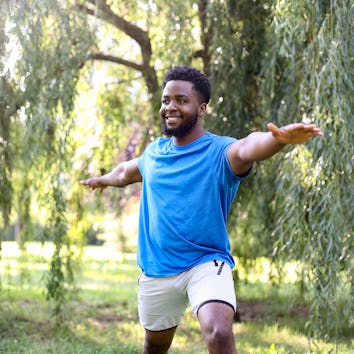 Young man exercising yoga in a park. About 25 years old, African male.