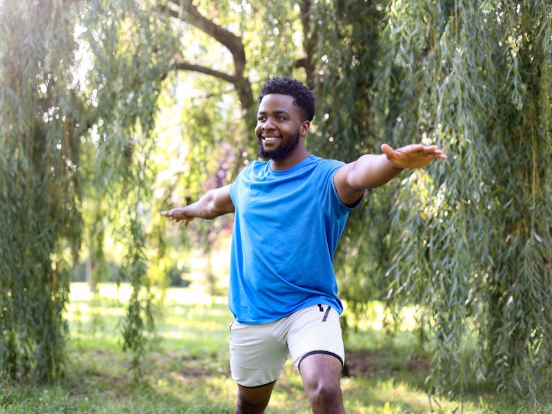 Young man exercising yoga in a park. About 25 years old, African male.