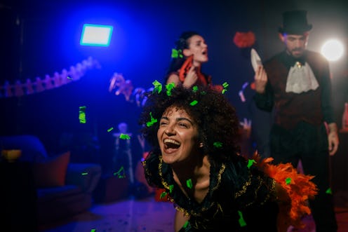 Portrait of charming young woman dancing in costume during a fun Halloween party with friends.