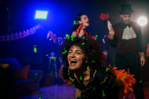 Portrait of charming young woman dancing in costume during a fun Halloween party with friends.