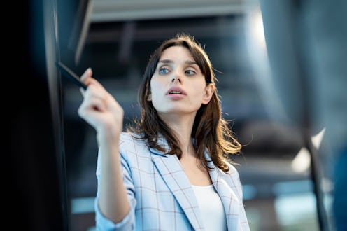 A female business development manager presents business information on a digital display screen to a...