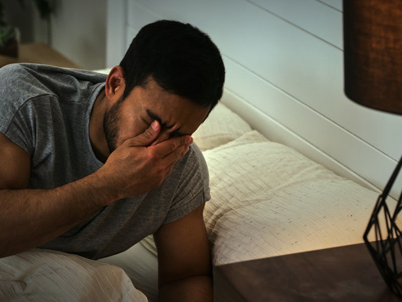 Headache, depression and man in a bed frustrated by insomnia, anxiety or sleep paralysis. Fatigue, c...
