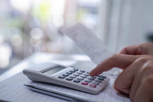 Young woman checking bill and use calculator at home.