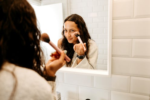 Young woman applying make up in the morning in the bathroom