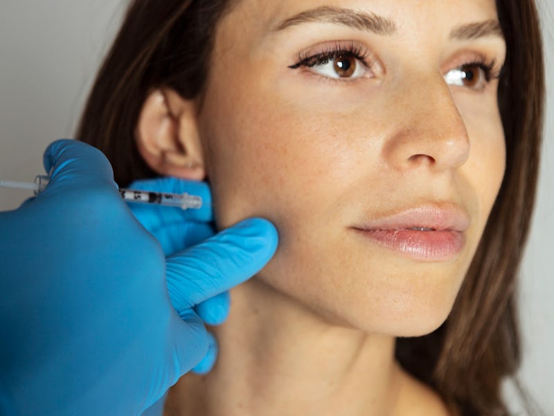 Woman with teeth clenching issue getting a shot of botox into the jaw muscle to relax it